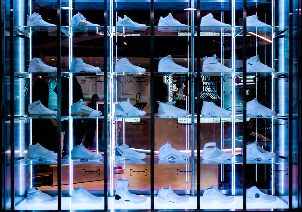 Colección de zapatillas blancas en perchero de cristal