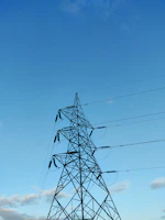 Photo of a secured pylon structure against a clear blue sky in Yopougon.