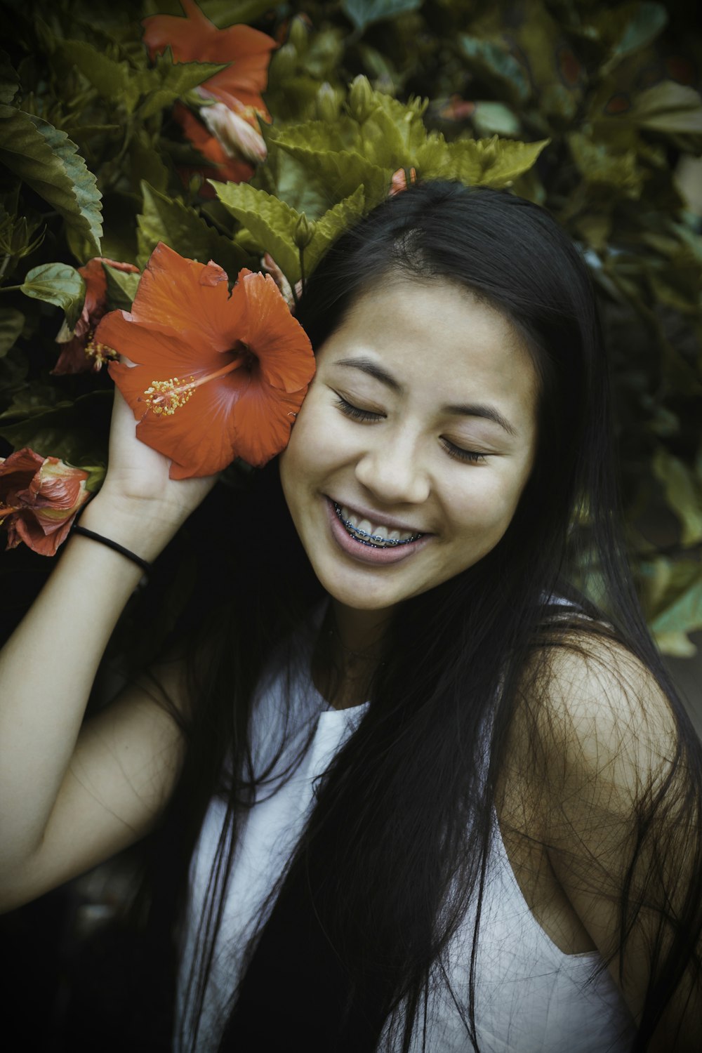 smiling woman holding red hibiscus