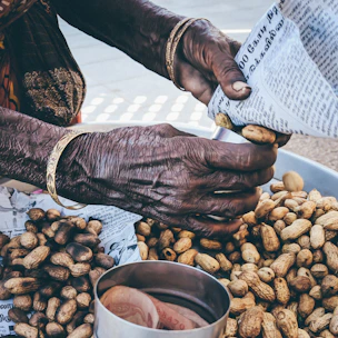 Artisan hands packaging traditional peanut caramel snacks in elegant red-gold wrappers.