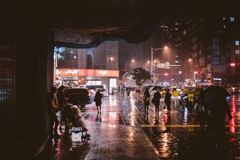 group of people walking on sidewalk during nighttime