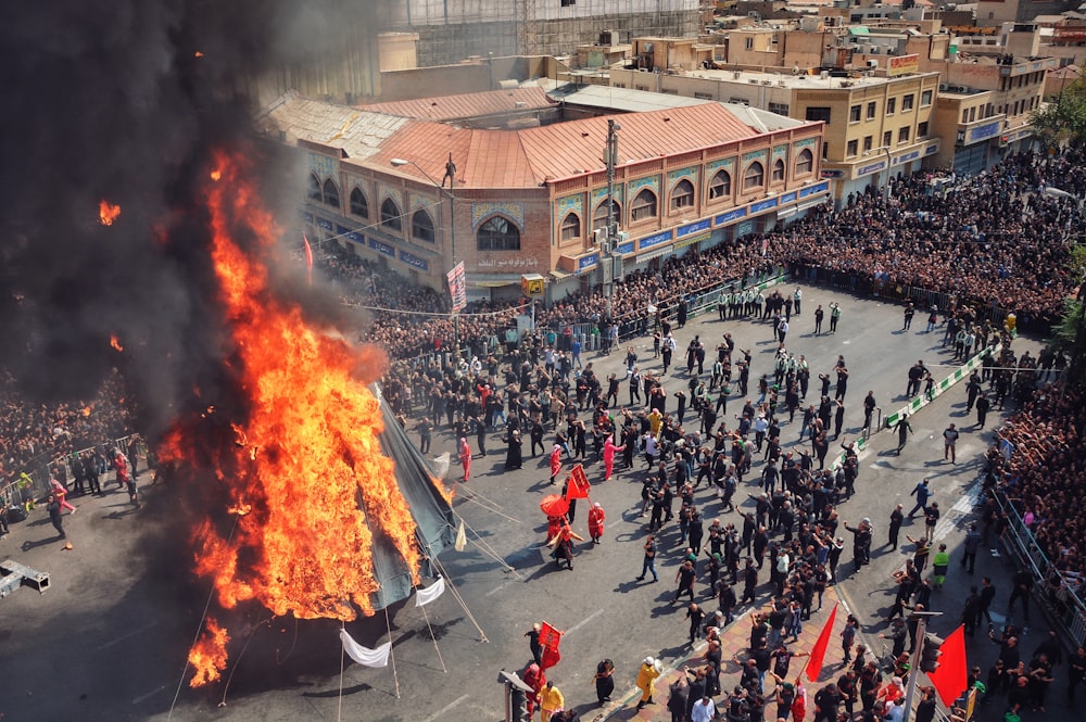 group of people standing surrounded on burning tipi tent during daytime