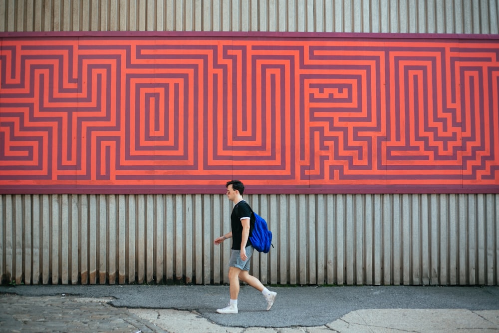 man carrying blue backpack walking along pathway