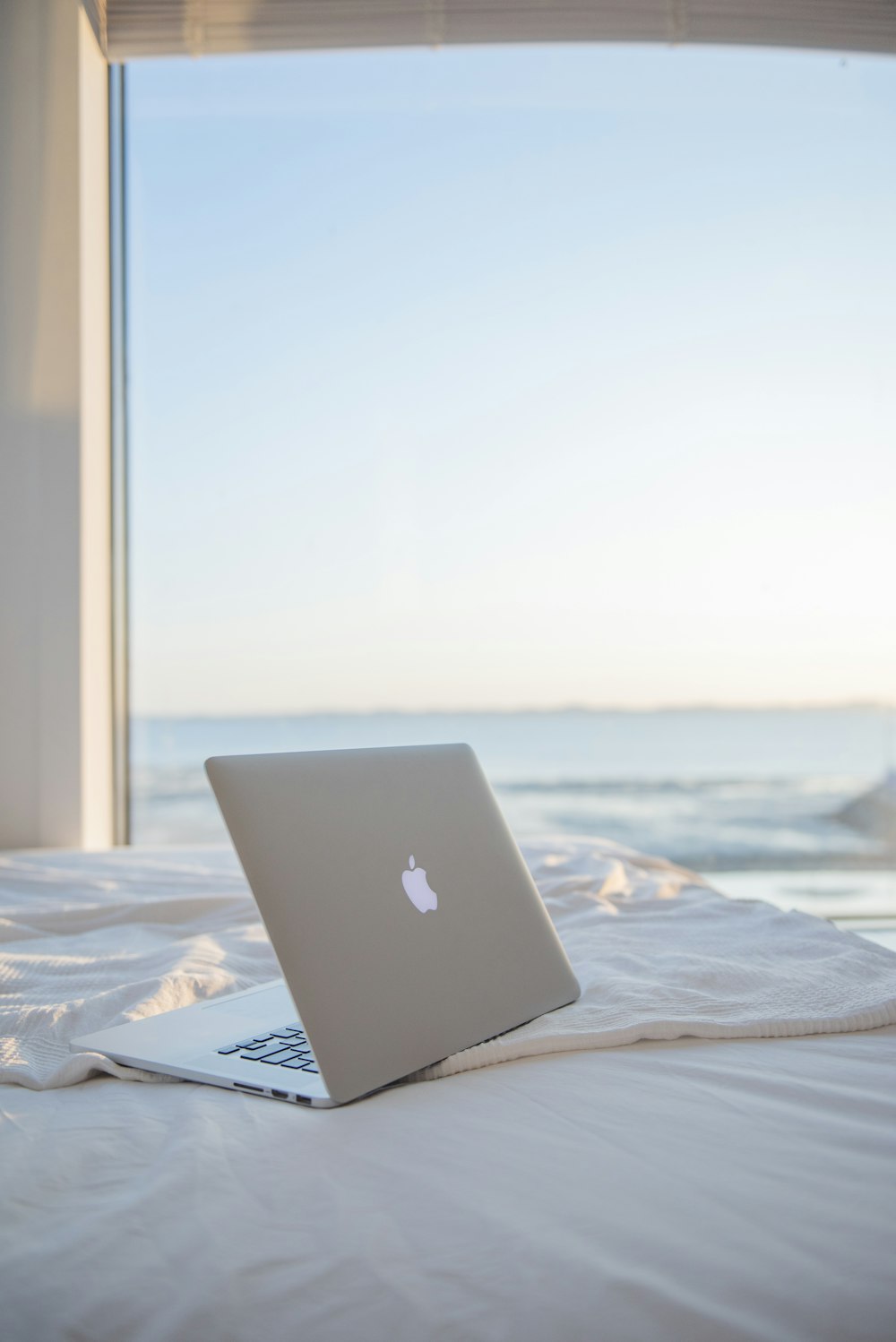 silver MacBook on white bed