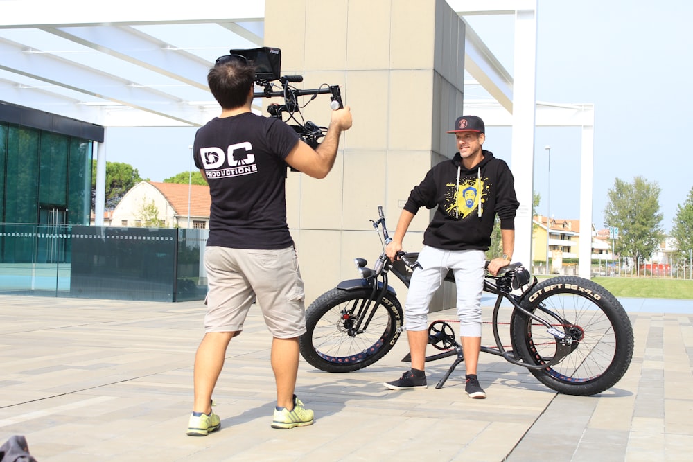 man taking video in person leaning on bike