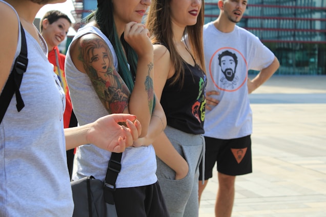 A group of diverse young adults confidently wearing bold graphic t-shirts in an urban street setting.