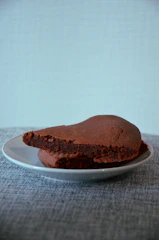 A rich, fudgy brownie fudge square resting on a pastel blue napkin with a bite taken out.