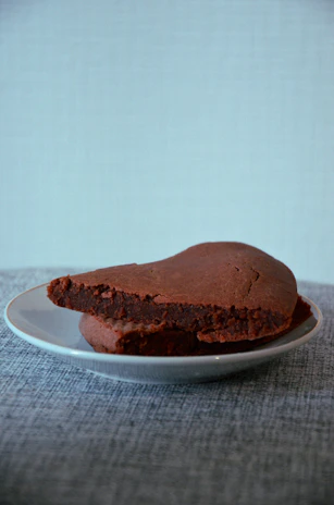 A rich, fudgy brownie fudge slice on a rustic wooden plate with a warm-toned napkin.