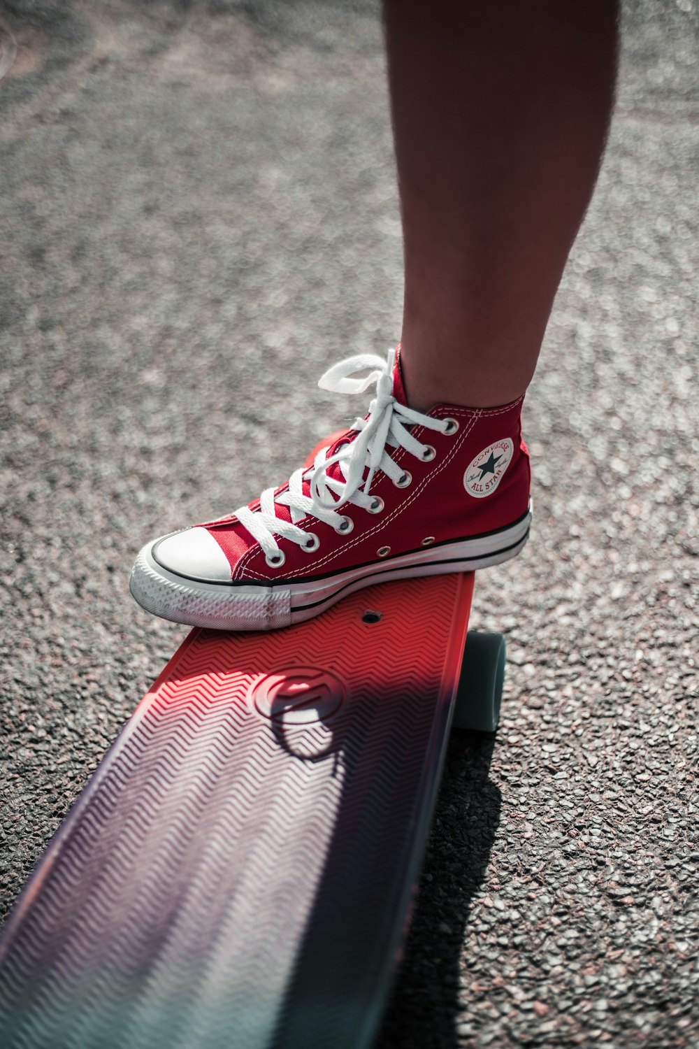 personne portant une chaussure montante Converse All-Star rouge