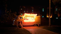 The Retroscoops truck glowing under string lights at an evening community event, with happy customers lined up.