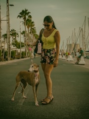 Sophisticated woman walking her pampered dog in a lush Naples garden.