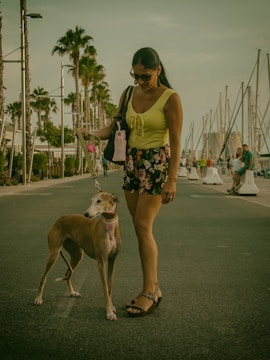 Sophisticated woman walking her pampered dog in a lush Naples garden.