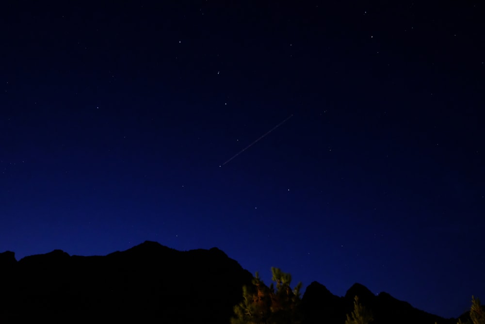 a night sky with a plane flying in the distance