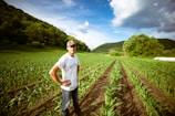A smiling small-scale farmer proudly standing in a lush green field.