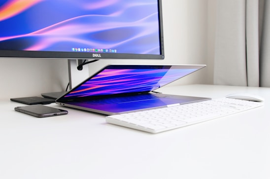 A clean, minimalist workspace with a laptop displaying environmental data charts, set against a white background with dark teal accents.