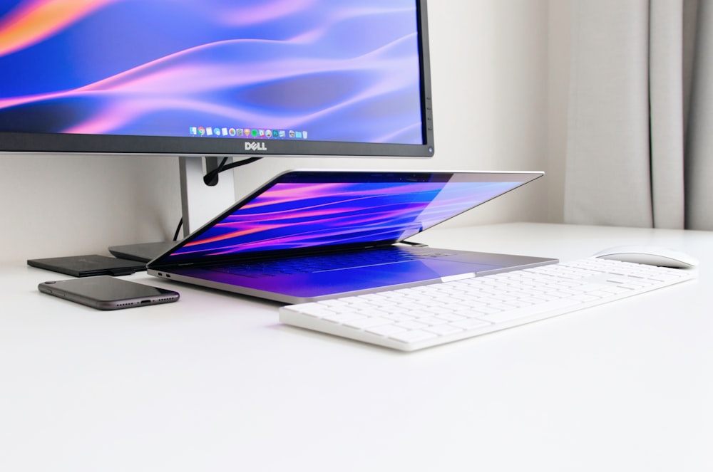 monitor Dell ligado na mesa em frente ao laptop, teclado e mouse
