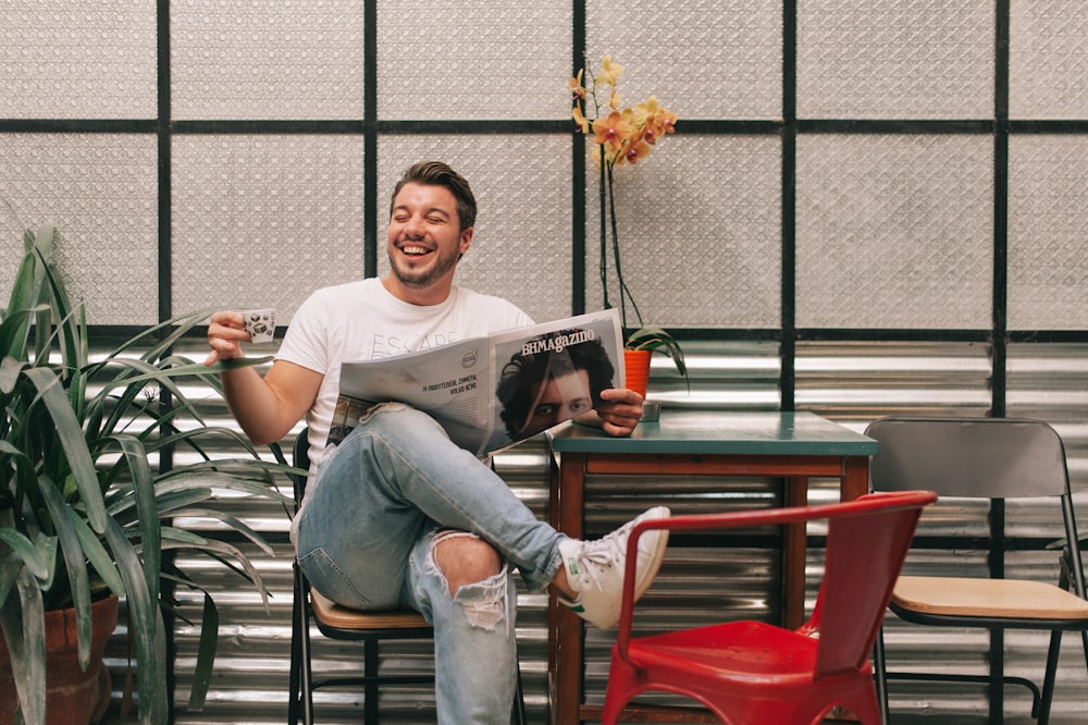 man sitting beside red plastic chair