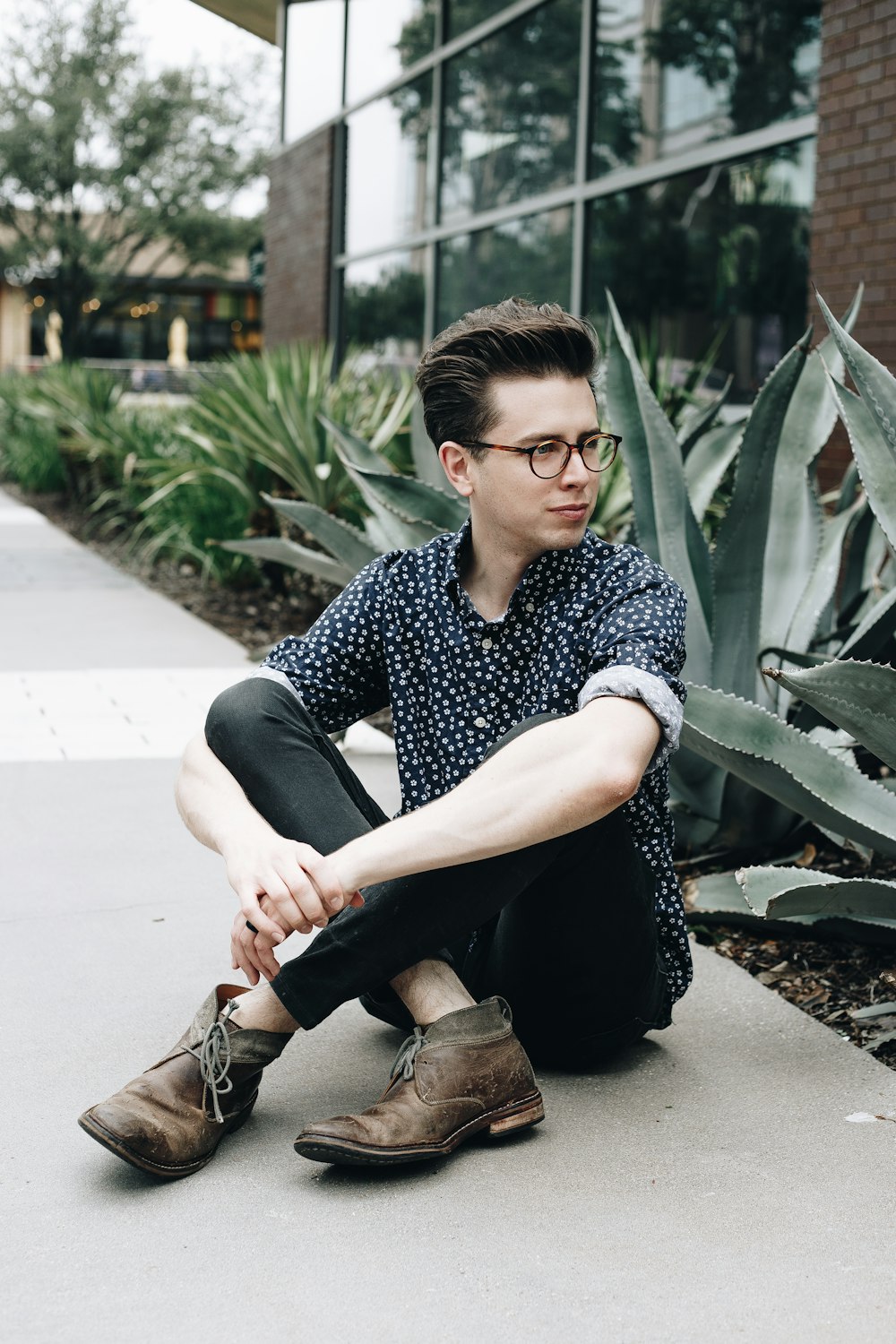 man sitting near green-leafed plant