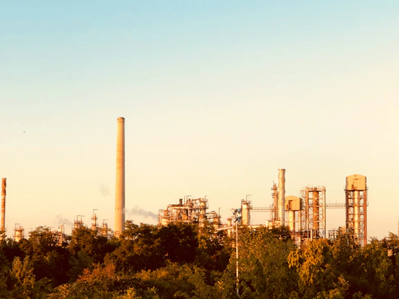 A panoramic view of a Ras Al Khaimah cement plant with golden sunlight highlighting the industrial structures.