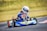 Young karting driver smiling with helmet in hand at Apexweek Racing School Mexico.