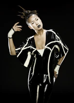 A model standing against a dark urban backdrop, wearing a futuristic streetwear ensemble with electric red glow details.