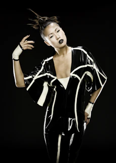 Model wearing oversized gothic streetwear with glowing red accents against a black gradient backdrop.