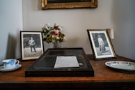 A delicate arrangement of flowers and personal mementos on a wooden table.