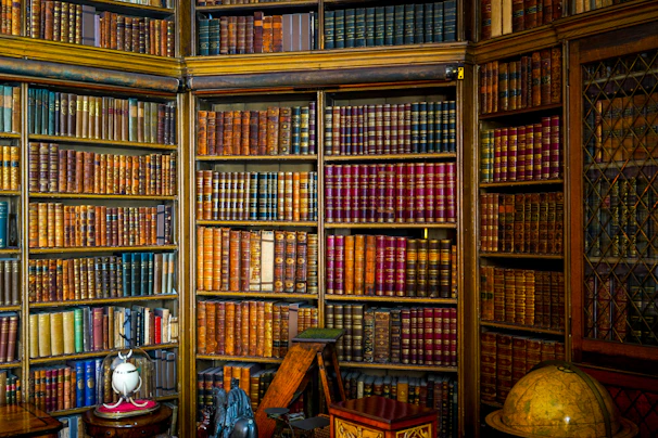A moody library corner with tall shelves filled with aged volumes and a vintage globe.