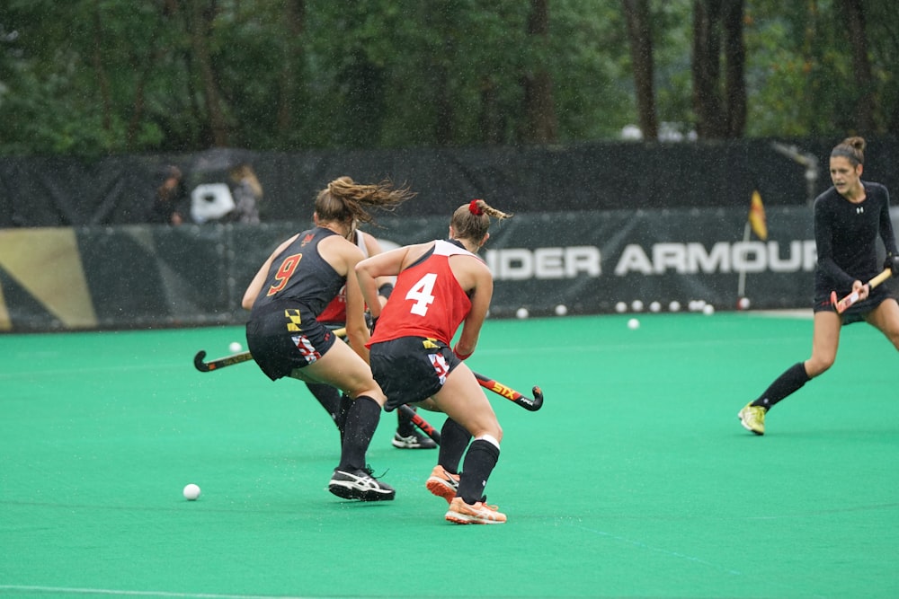 three women playing hockey game during daytime