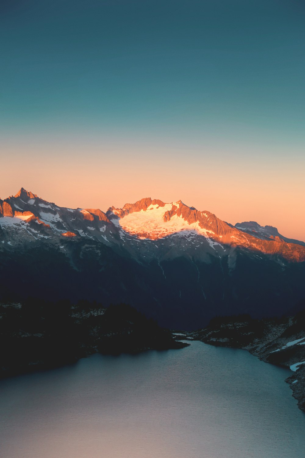 snow capped mountain near lake at daytime