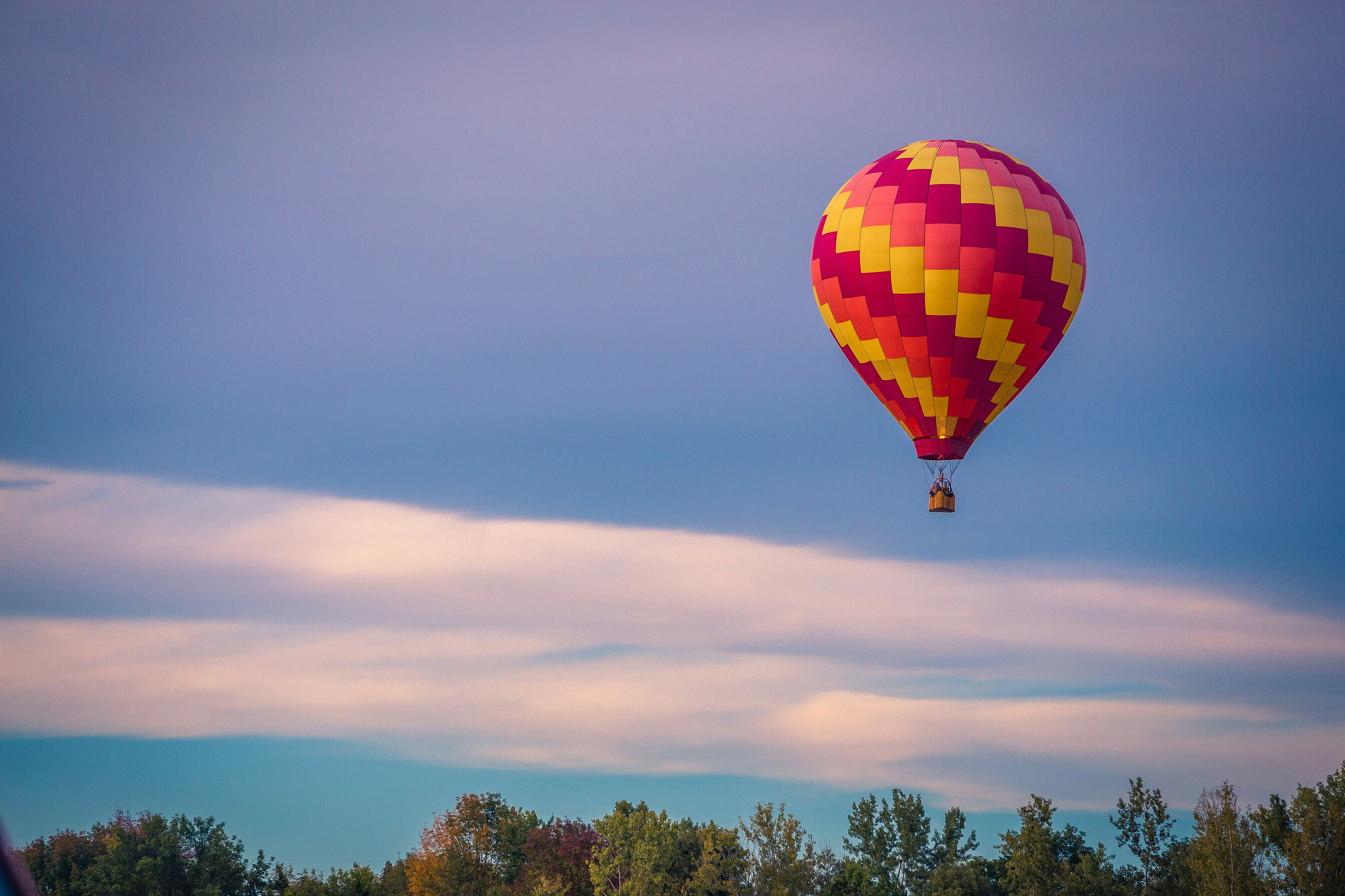 pink and yellow air balloon over trees, 