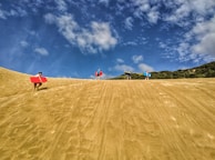 Children happily carrying their small beginner boards across the sandy shore.