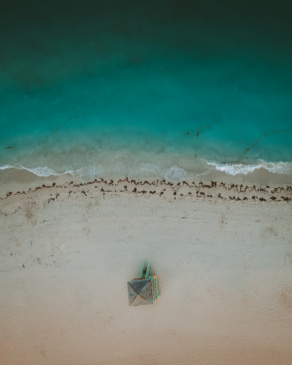 an aerial view of a beach with a kite in the sand