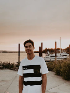 Portrait of Yassin Papito standing by the Mombasa coastline, with ships and the busy port in the background at sunset.