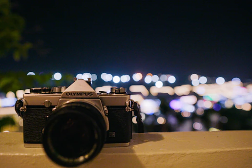 A sleek, minimalist film camera lens reflecting a cinematic cityscape at dusk.