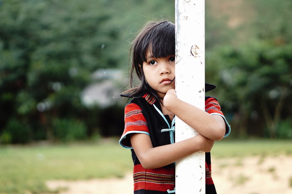 girl hugging white metal post