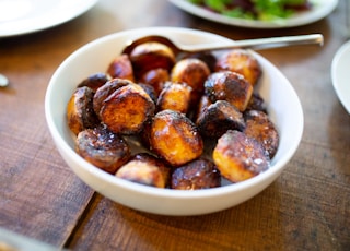 selective focus photography of glazed nuts inside white ceramic saucer