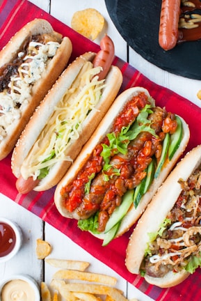 A colorful plate of vegetarian hot dogs topped with fresh vegetables and sauces, served with crispy fries.