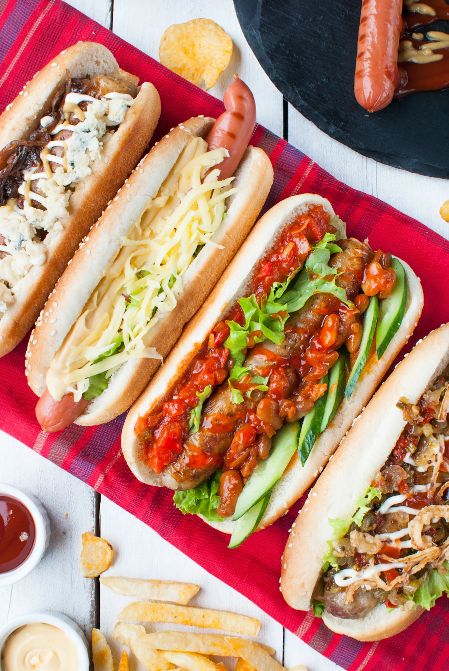 Two fully loaded hot dogs with slaw and chili on a red checked napkin