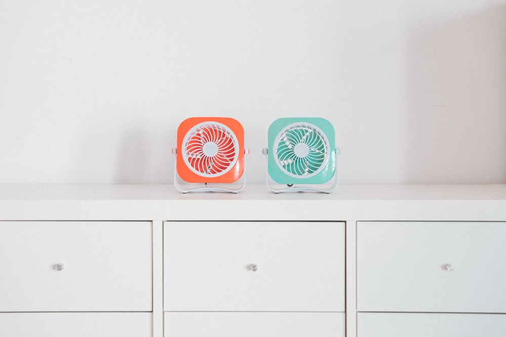 two red and green portable fans on white desk