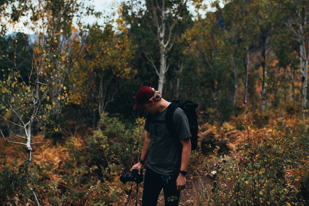 man holding DSLR camera in the middle of the forest