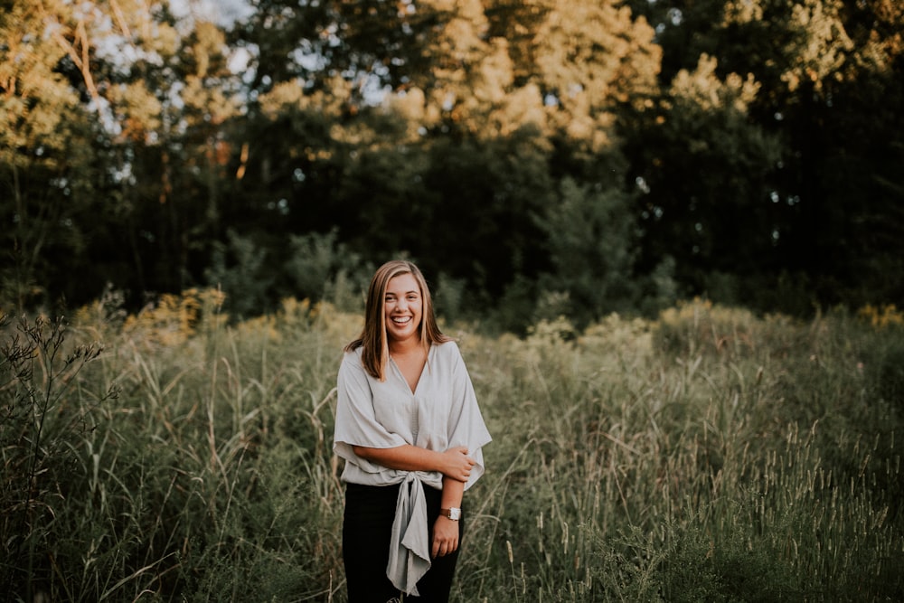 standing woman smiling near trees at daytime