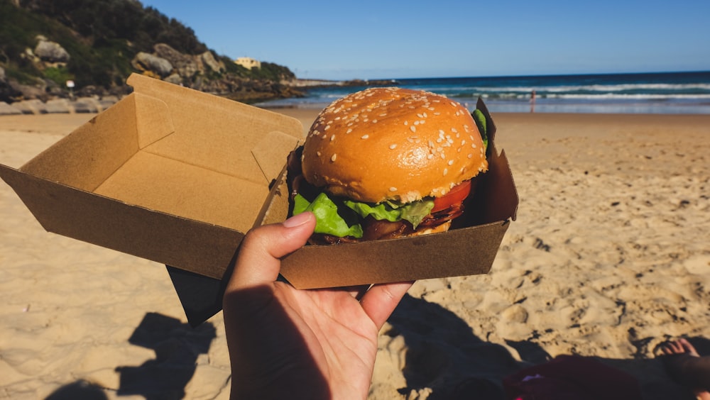 person holding box with burger and lettuce