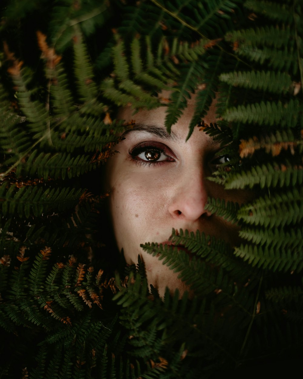 person's face covered with fern plant