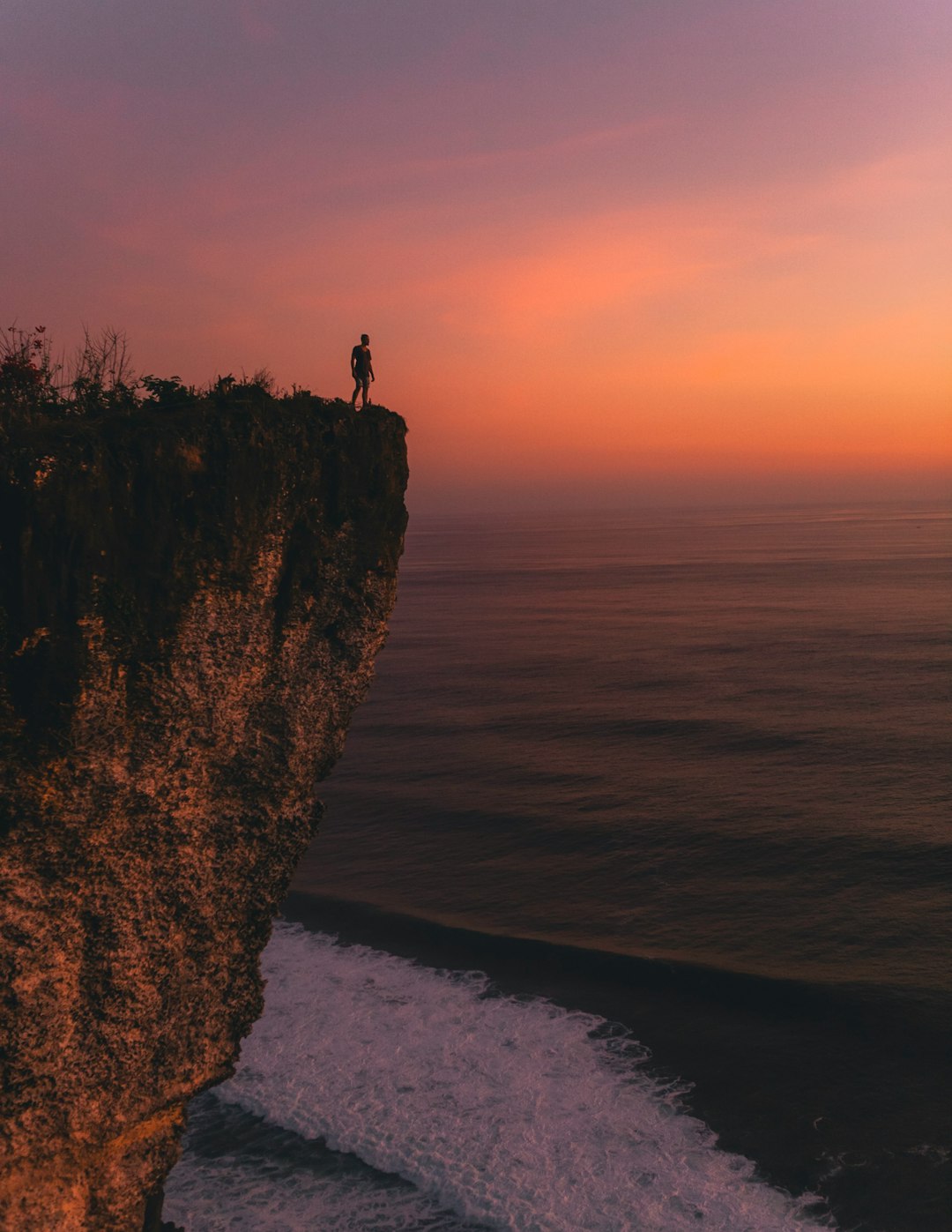 person standing on cliff during sunset