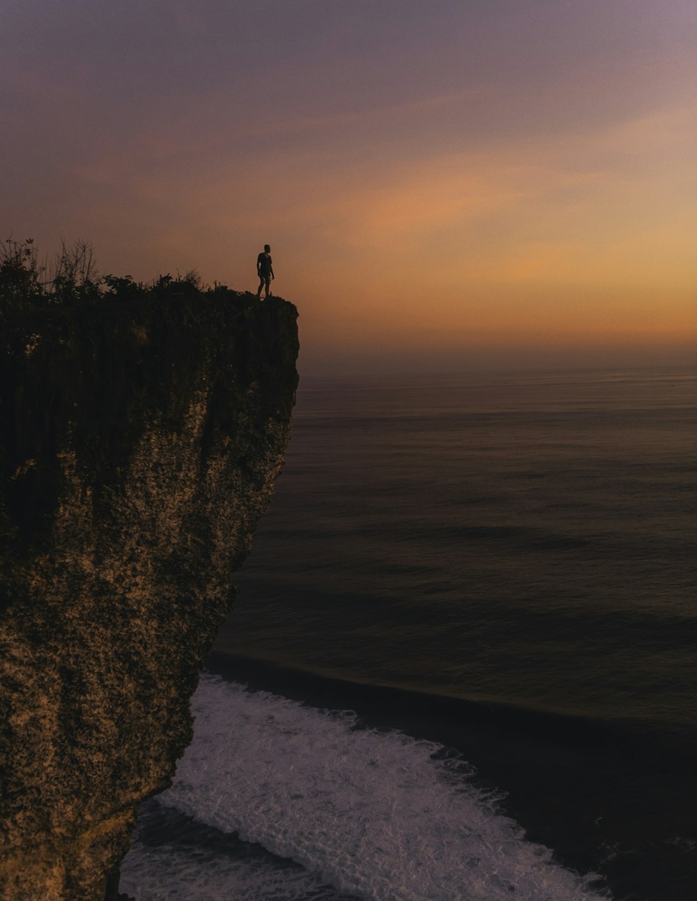 person standing on cliff during sunset