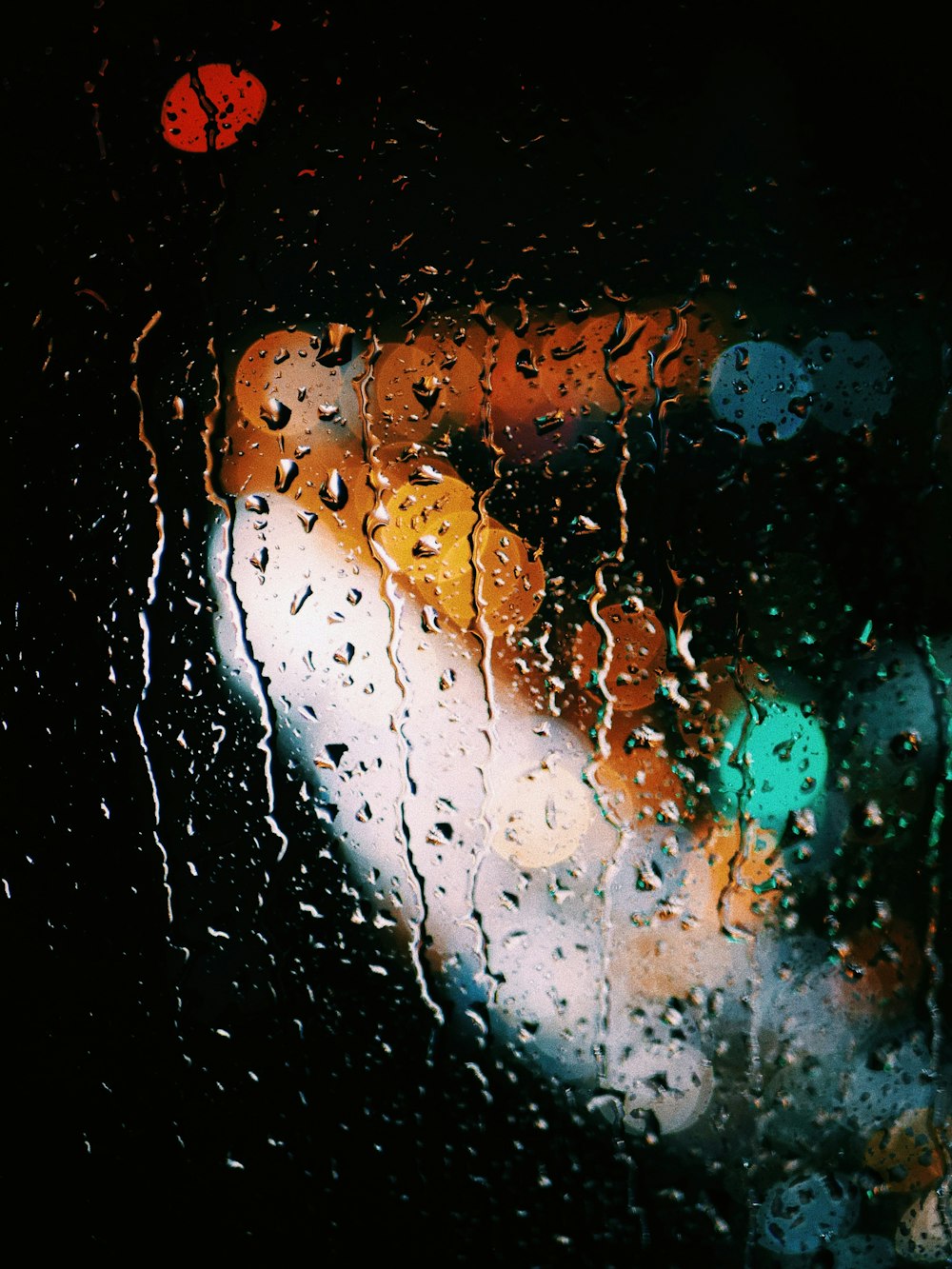 Un semáforo visto a través de una ventana cubierta de lluvia