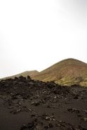 A sweeping landscape of volcanic terrain with a student photographing in the distance.