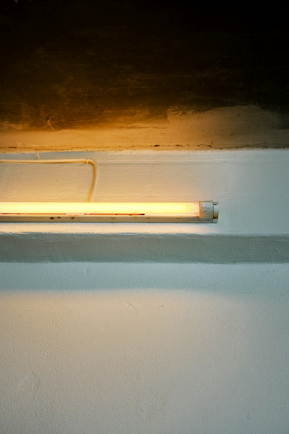 yellow fluorescent lamp mounted on white wall