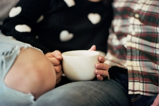 A cozy couple holding matching elegant black and pink mugs, sitting close together.